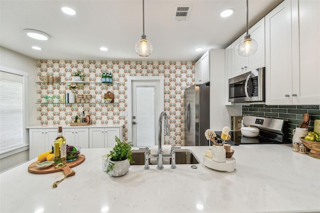 2452 Bayshore Blvd, Dunedin, FL 34698 - kitchen featuring stainless steel appliances, decorative light fixtures, white cabinets, tasteful backsplash, and recessed lighting
