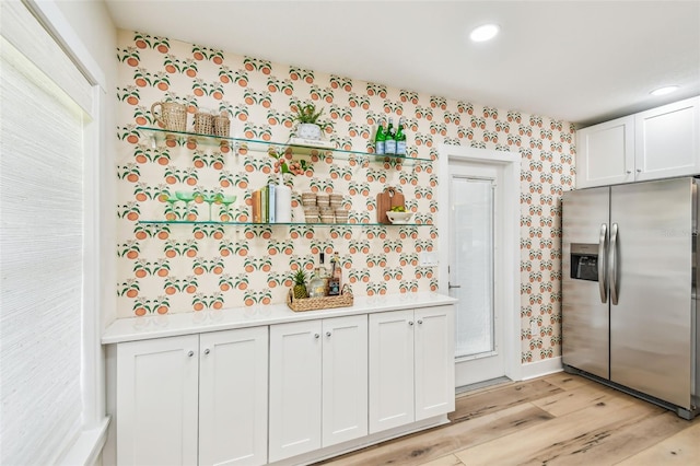 2452 Bayshore Blvd, Dunedin, FL 34698 - kitchen with stainless steel fridge, wallpapered walls, light wood-style floors, light countertops, and white cabinets