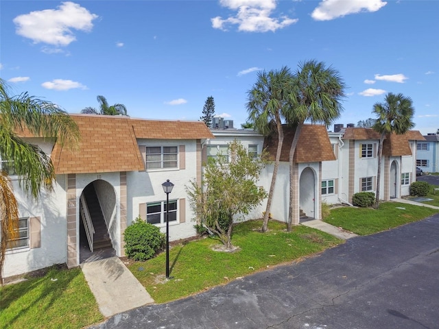 345 S Mcmullen Booth Rd Unit 142, Clearwater, FL 33759 - view of front of property featuring a shingled roof, mansard roof, a front yard, and stucco siding