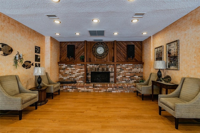 345 S Mcmullen Booth Rd Unit 142, Clearwater, FL 33759 - living room featuring light wood finished floors, a textured ceiling, a brick fireplace, a textured wall, and recessed lighting