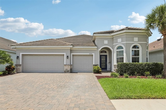 12004 Cinnamon Fern Dr, Riverview, FL 33579 - mediterranean / spanish-style house with decorative driveway, stone siding, and an attached garage