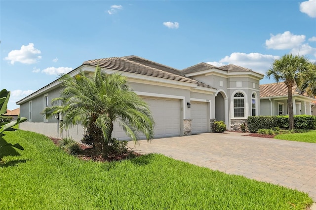 12004 Cinnamon Fern Dr, Riverview, FL 33579 - mediterranean / spanish home featuring an attached garage, decorative driveway, a front lawn, and a tiled roof