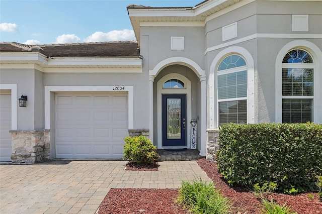 12004 Cinnamon Fern Dr, Riverview, FL 33579 - entrance to property featuring stucco siding, stone siding, an attached garage, and driveway
