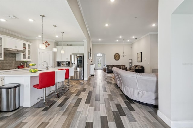 12004 Cinnamon Fern Dr, Riverview, FL 33579 - kitchen featuring stainless steel refrigerator with ice dispenser, light countertops, arched walkways, wood finished floors, and tasteful backsplash