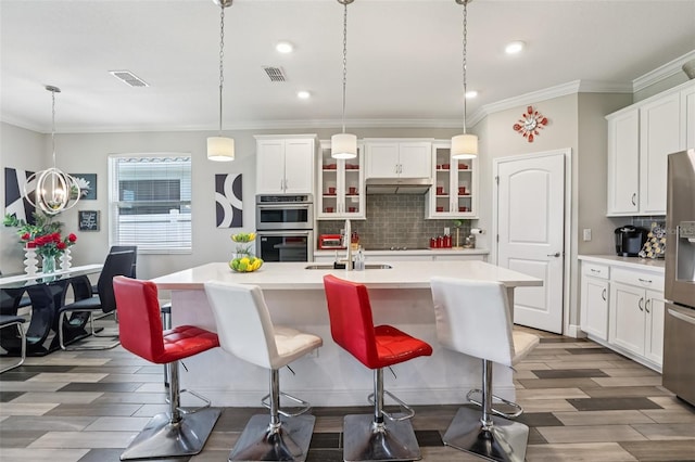 12004 Cinnamon Fern Dr, Riverview, FL 33579 - kitchen featuring stainless steel appliances, under cabinet range hood, backsplash, light countertops, and crown molding