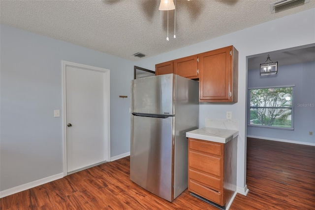 1717 Atrium Dr, Sun City Center, FL 33573 - kitchen with freestanding refrigerator, dark wood-style floors, light countertops, brown cabinets, and a textured ceiling