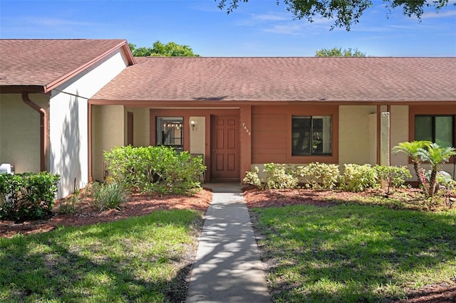 7433 Greystone Dr Unit 7433, Hudson, FL 34667 - view of front of house featuring a shingled roof, a front lawn, and stucco siding