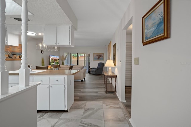 7433 Greystone Dr Unit 7433, Hudson, FL 34667 - kitchen with a peninsula, white cabinetry, light marble finish flooring, light countertops, and ornate columns