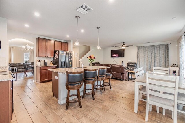 2073 Branding Iron Way, New Port Richey, FL 34655 - kitchen with stainless steel fridge, open floor plan, brown cabinetry, ceiling fan, and arched walkways
