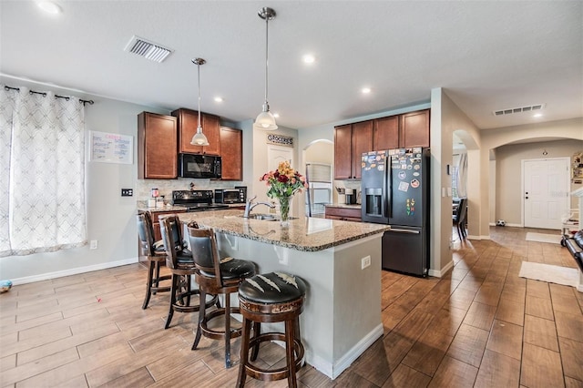 2073 Branding Iron Way, New Port Richey, FL 34655 - kitchen featuring fridge with ice dispenser, arched walkways, black microwave, light wood-style flooring, and a breakfast bar