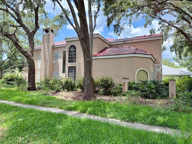16006 Armistead Ln, Odessa, FL 33556 - view of property exterior featuring stucco siding, a chimney, and a tiled roof