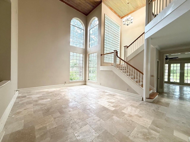 16006 Armistead Ln, Odessa, FL 33556 - unfurnished living room with ornamental molding, stone tile floors, a towering ceiling, plenty of natural light, and a chandelier