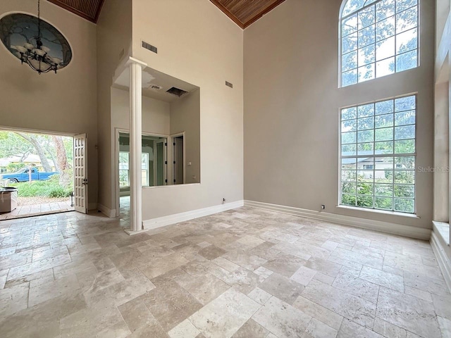 16006 Armistead Ln, Odessa, FL 33556 - unfurnished room with stone tile floors, a high ceiling, plenty of natural light, and a chandelier