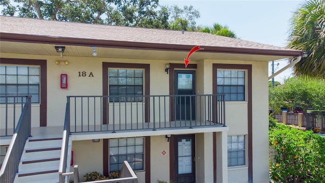 2400 Winding Creek Blvd Unit Bldg18A # 210, Clearwater, FL 33761 - view of front of house with stucco siding, covered porch, stairway, and roof with shingles