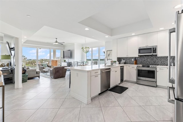 706 Bayway Blvd Unit 503, Clearwater, FL 33767 - kitchen featuring appliances with stainless steel finishes, light tile patterned flooring, a peninsula, a tray ceiling, and open floor plan