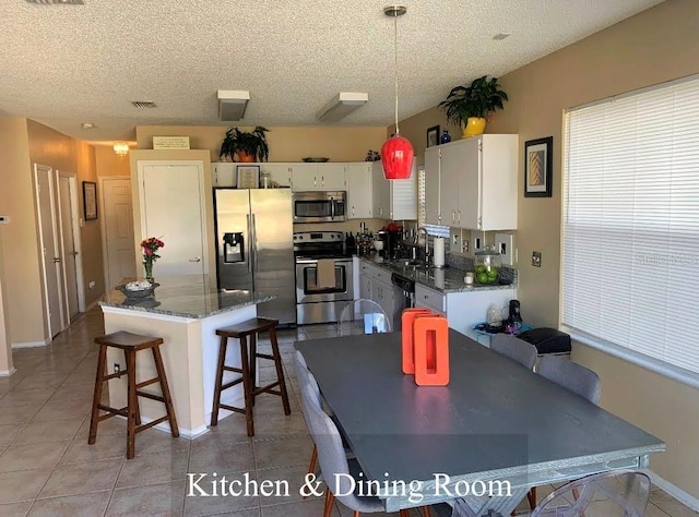 5139 Corvette Dr, Tampa, FL 33624 - kitchen with stainless steel appliances, white cabinets, decorative light fixtures, a kitchen breakfast bar, and dark stone countertops