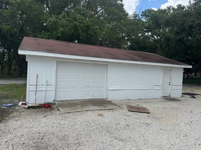 17048 State Road 54, Lutz, FL 33558 - detached garage with driveway and view of wooded area