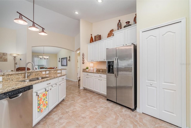 13194 Royal Pines Ave, Riverview, FL 33579 - kitchen with stainless steel appliances, arched walkways, white cabinets, light stone countertops, and lofted ceiling