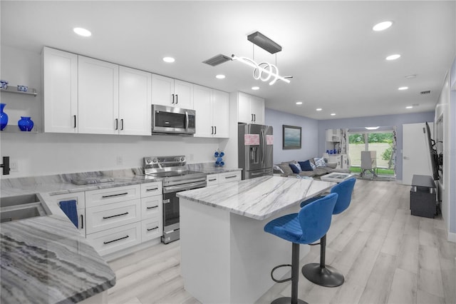 1701 Pinehurst Rd Unit 33E, Dunedin, FL 34698 - kitchen with appliances with stainless steel finishes, open floor plan, a kitchen island, open shelves, and white cabinets