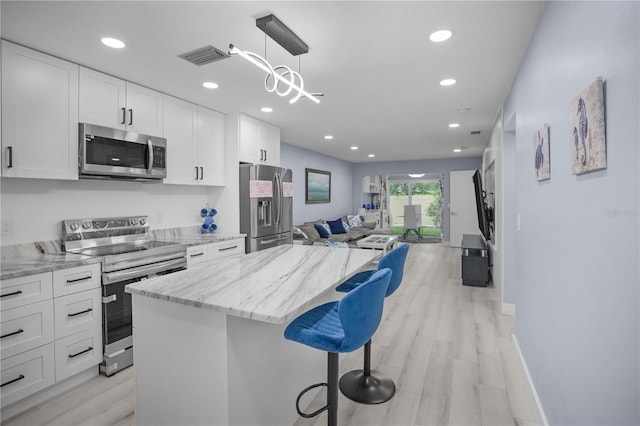 1701 Pinehurst Rd Unit 33E, Dunedin, FL 34698 - kitchen featuring appliances with stainless steel finishes, open floor plan, a center island, white cabinetry, and recessed lighting