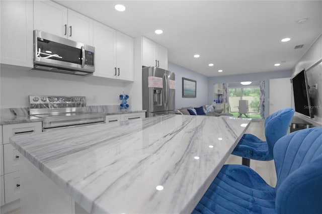 1701 Pinehurst Rd Unit 33E, Dunedin, FL 34698 - kitchen with stainless steel appliances, open floor plan, white cabinets, a breakfast bar area, and recessed lighting