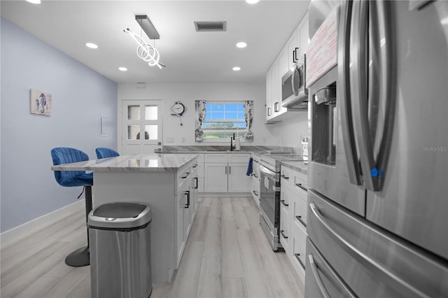 1701 Pinehurst Rd Unit 33E, Dunedin, FL 34698 - kitchen with appliances with stainless steel finishes, a breakfast bar area, a center island, light stone countertops, and white cabinets