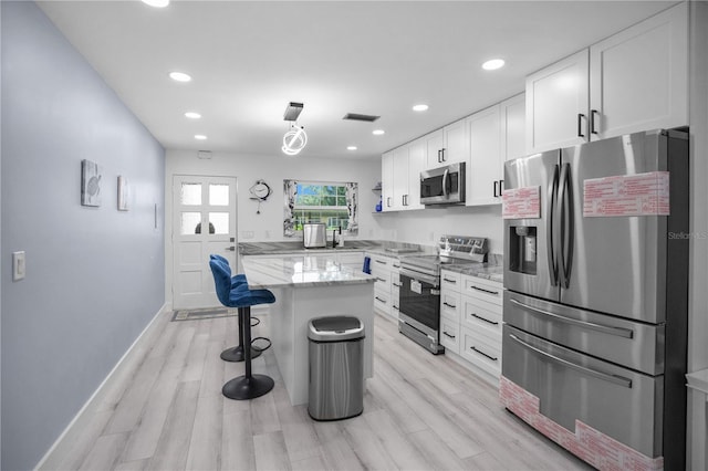 1701 Pinehurst Rd Unit 33E, Dunedin, FL 34698 - kitchen with appliances with stainless steel finishes, recessed lighting, a breakfast bar, white cabinets, and light stone counters