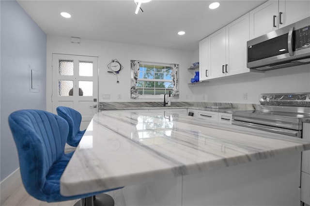 1701 Pinehurst Rd Unit 33E, Dunedin, FL 34698 - kitchen featuring stainless steel appliances, white cabinetry, light stone counters, recessed lighting, and open shelves