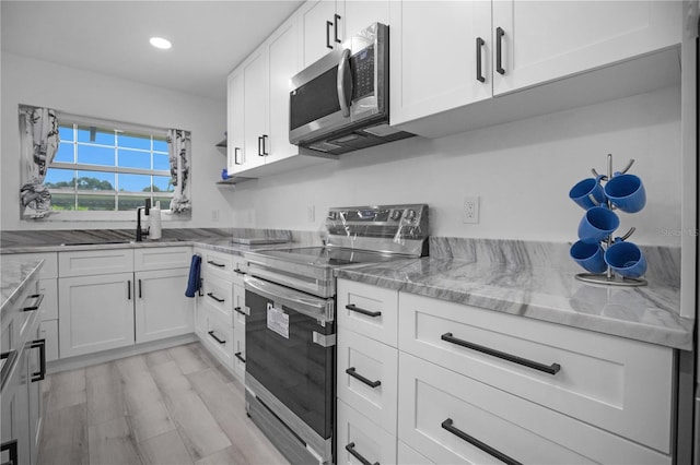 1701 Pinehurst Rd Unit 33E, Dunedin, FL 34698 - kitchen featuring stainless steel appliances, white cabinetry, light stone countertops, and recessed lighting