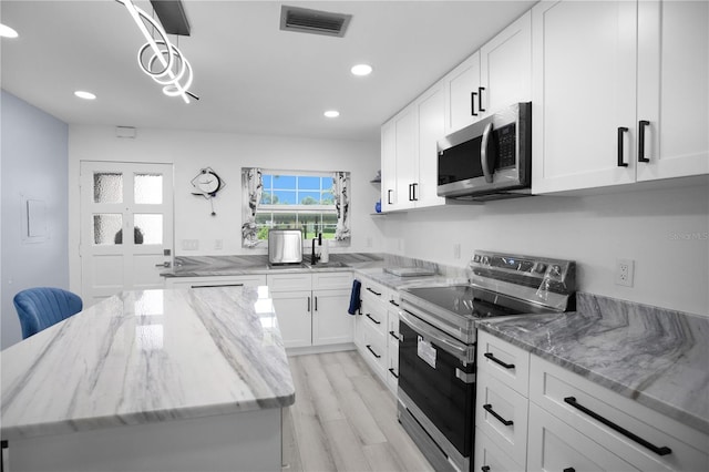 1701 Pinehurst Rd Unit 33E, Dunedin, FL 34698 - kitchen featuring appliances with stainless steel finishes, white cabinets, recessed lighting, light wood finished floors, and light stone countertops