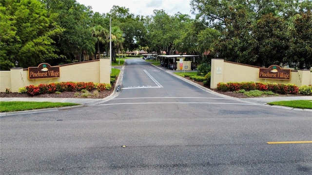 1701 Pinehurst Rd Unit 33E, Dunedin, FL 34698 - view of asphalt road with view of wooded area, street lights, and curbs