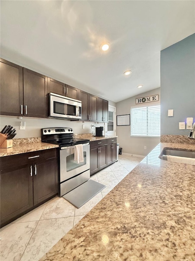630 Timber Bay Cir W, Oldsmar, FL 34677 - kitchen with stainless steel appliances, dark brown cabinets, lofted ceiling, light tile patterned flooring, and light stone countertops