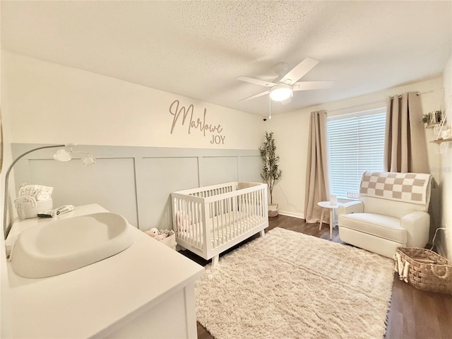 630 Timber Bay Cir W, Oldsmar, FL 34677 - bedroom featuring a nursery area, a textured ceiling, dark wood-style flooring, and a ceiling fan