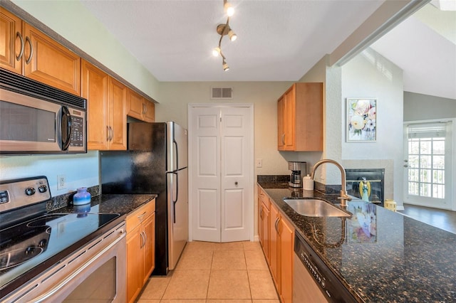 3301 Haviland Ct Unit 301, Palm Harbor, FL 34684 - kitchen featuring appliances with stainless steel finishes, dark stone countertops, light tile patterned flooring, a glass covered fireplace, and brown cabinets