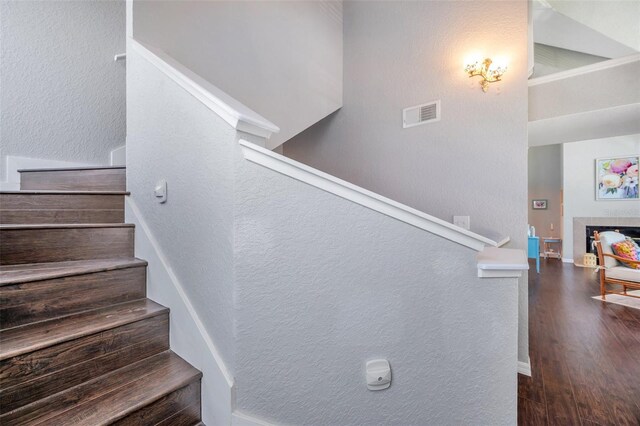 3301 Haviland Ct Unit 301, Palm Harbor, FL 34684 - stairway featuring wood finished floors, a textured wall, and a tiled fireplace