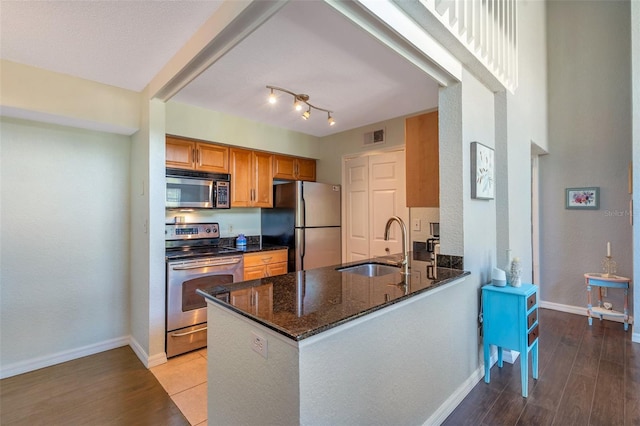 3301 Haviland Ct Unit 301, Palm Harbor, FL 34684 - kitchen featuring stainless steel appliances, brown cabinetry, light wood finished floors, and dark stone counters