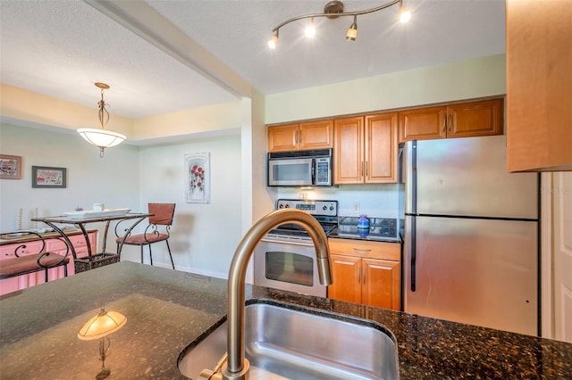 3301 Haviland Ct Unit 301, Palm Harbor, FL 34684 - kitchen featuring appliances with stainless steel finishes, brown cabinetry, decorative light fixtures, and dark stone counters