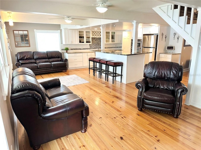 20111 County Line Rd, Lutz, FL 33558 - living area with ceiling fan, light wood finished floors, decorative columns, and stairs
