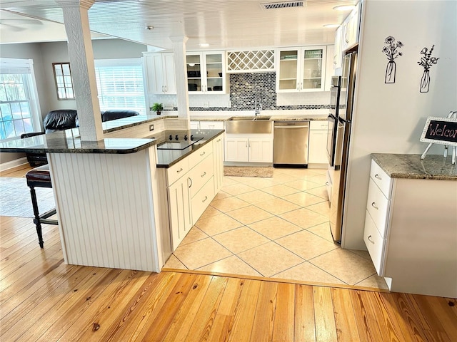 20111 County Line Rd, Lutz, FL 33558 - kitchen featuring stainless steel dishwasher, a breakfast bar area, decorative backsplash, glass insert cabinets, and light wood-type flooring