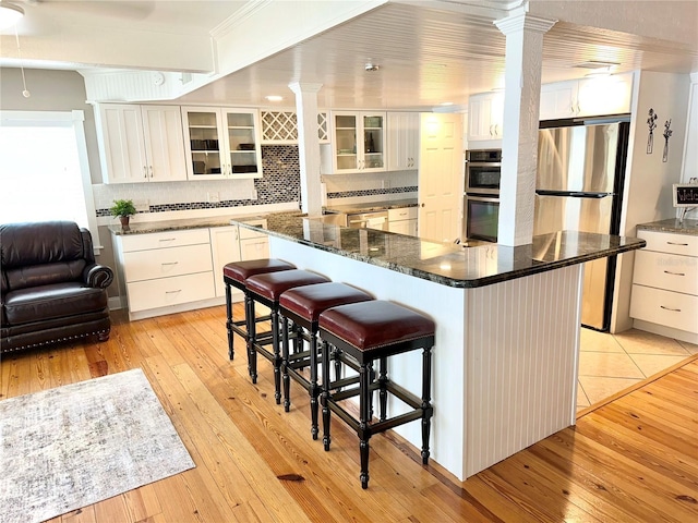20111 County Line Rd, Lutz, FL 33558 - kitchen featuring stainless steel appliances, ornate columns, light wood-type flooring, and decorative backsplash