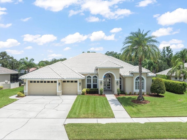 6905 Arabian Rd, Odessa, FL 33556 - mediterranean / spanish-style home featuring a garage, concrete driveway, a front lawn, stucco siding, and french doors