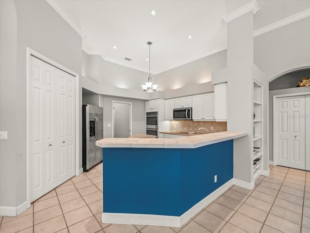 6905 Arabian Rd, Odessa, FL 33556 - kitchen featuring appliances with stainless steel finishes, a peninsula, tile counters, crown molding, and white cabinetry