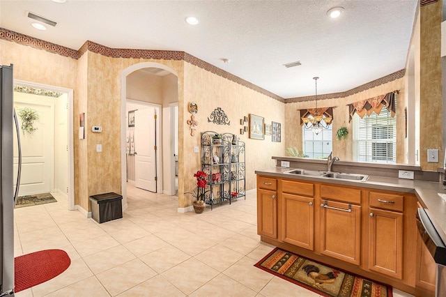6041 Sandhill Ridge Dr, Lithia, FL 33547 - kitchen with arched walkways, a chandelier, brown cabinets, a peninsula, and appliances with stainless steel finishes