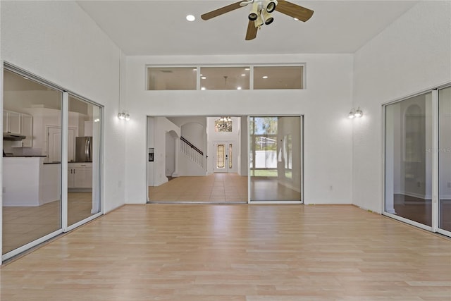 19206 Ivy Oak Way, Tampa, FL 33647 - spare room featuring light wood-type flooring, a high ceiling, stairway, and a ceiling fan