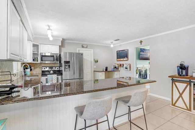 901 Strawberry Ln, Brandon, FL 33511 - kitchen featuring appliances with stainless steel finishes, a peninsula, dark stone counters, decorative backsplash, and white cabinetry
