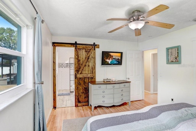 901 Strawberry Ln, Brandon, FL 33511 - bedroom featuring a barn door, wood finished floors, ceiling fan, and connected bathroom