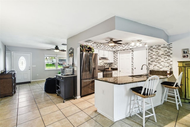 8823 Aruba Ln, Port Richey, FL 34668 - kitchen with appliances with stainless steel finishes, a peninsula, a ceiling fan, dark stone countertops, and white cabinets