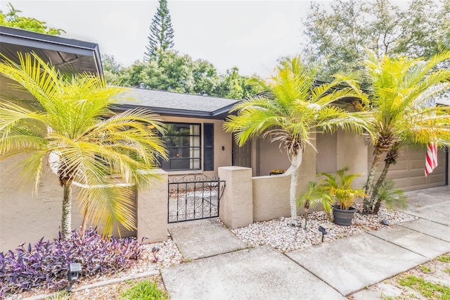 2199 Blue Tern Dr, Palm Harbor, FL 34683 - view of exterior entry featuring stucco siding, a gate, concrete driveway, and a garage