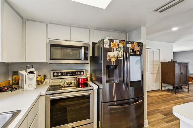 2199 Blue Tern Dr, Palm Harbor, FL 34683 - kitchen with stainless steel appliances, white cabinets, light countertops, and light wood-style floors