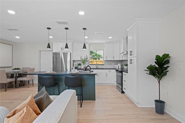 1707 Solon Ave, Dunedin, FL 34698 - kitchen featuring stainless steel appliances, dark countertops, light wood finished floors, a breakfast bar area, and recessed lighting